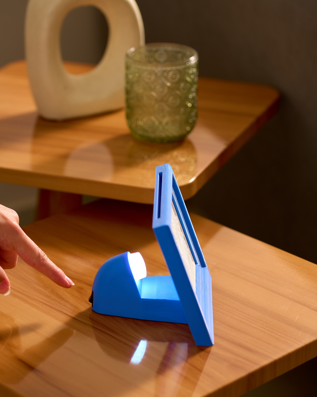blue 3D printed classic heirloom style LED backlit photo frame with personalized glowing family picture on a wooden table from side point of view .