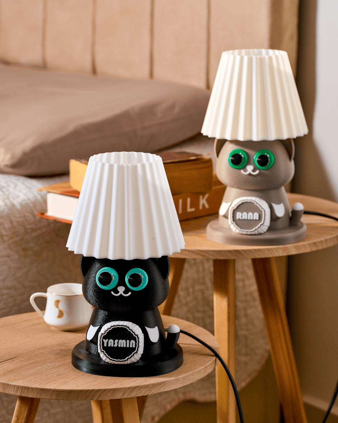 Two cat lamps with lampshades on a wooden table.